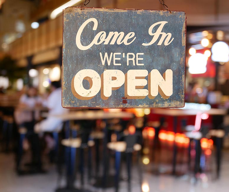Close up of sign on window of a restaurant/bar/café stating Come in We're Open