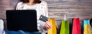 Woman sat at laptop with credit card and shopping bags highlighting the problem with customer returns